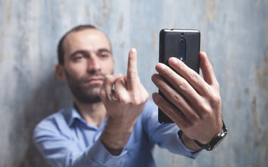 Man takes a selfie and shows middle finger at camera.
