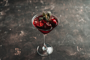 Cherry cocktail in martini glass with berries and mint leaves. Selective focus. Shallow depth of field.