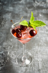 Cherry cocktail in martini glass with berries and mint leaves. Selective focus. Shallow depth of field.