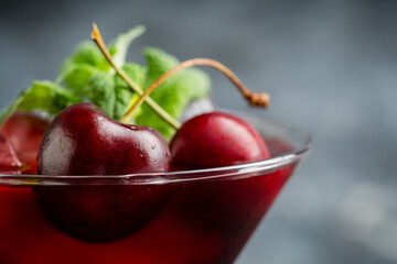 Cherry cocktail in martini glass with berries and mint leaves. Selective focus. Shallow depth of field.