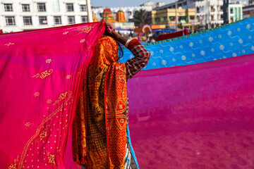 Indian women pilgrims drying their colorful sarees under sun after taking holy bath at puri beach.