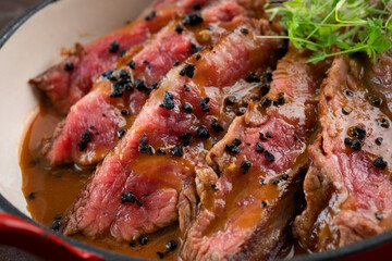 Sliced medium-rare beef tenderloin steak with sauce on a plate, close up