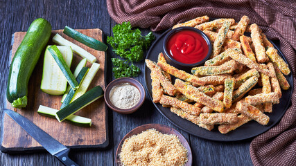 zucchini sticks on a black plate with ketchup
