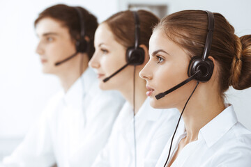 Call center. Beautiful young woman using headset and computer to help customers. Business concept