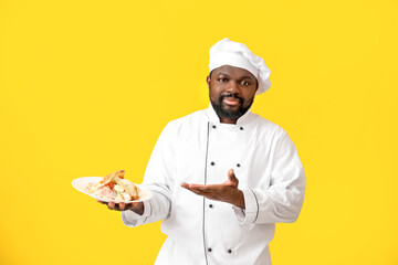 Male African-American chef with tasty dish on color background