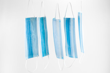 of some surgical masks hanging in a row isolated on white background