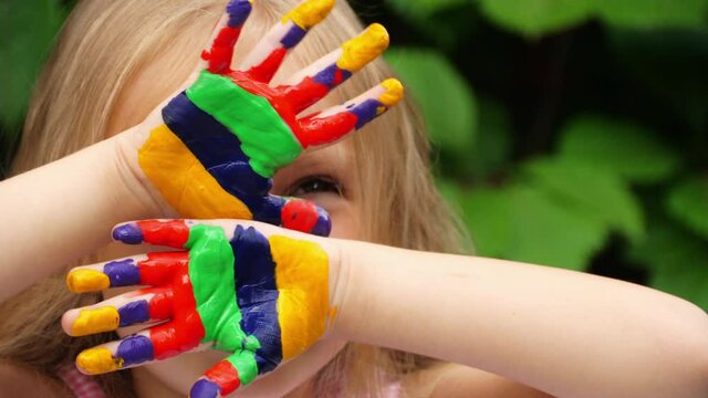 Painted hands of a child with bright colors! Painting and a child. Girl blonde artist