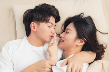 Obraz na płótnie Canvas A young asian couple was lying in bed, looking at each other very close