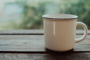 White vintage mug on the wooden table.