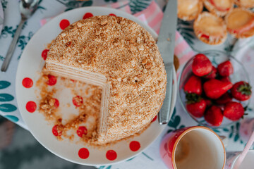 Home made honey cake on birthday party. Kid's birthday table with sweets, candies, cakes, and strawberries. Birthday party food.