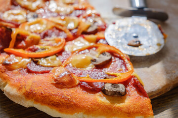 Cutting pepperoni pizza on slices with knife.