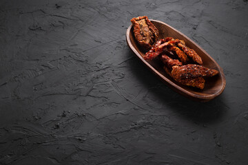 Dried tomatoes concept with wooden presentation board on black stone floor ( with copy space )