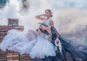 Pretty Asian Thai women holding beautiful garland in here hand and wearing traditional Thai dress costume according culture with the old brick wall at the ancient temple Chiangmai Thailand.
