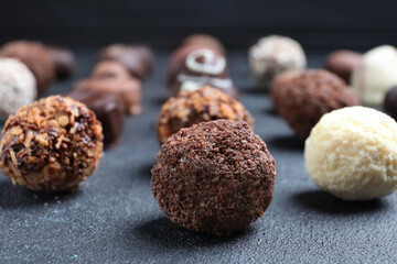 Different tasty chocolate candies on black table, closeup