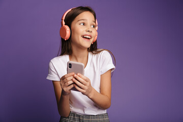 Photo of laughing girl using wireless headphones and mobile phone