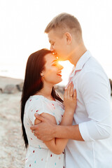 Loving couple in white clothes during a honeymoon at sea walk on the sand at a photoshoot Love Story, ocean coast, beach