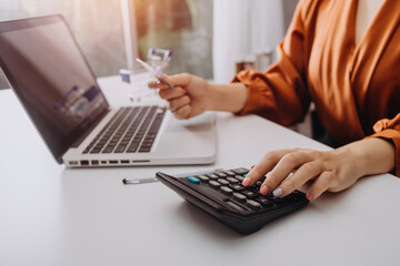 Businesswomen hands working with finances about cost and calculator and laptop with tablet, smartphone at office in morning light