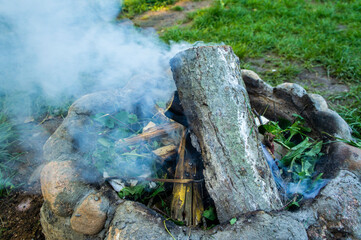 Old stone hearth with burning smoking firewood