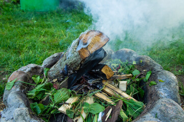 Old stone hearth with burning smoking firewood
