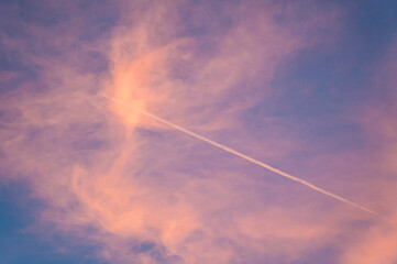 Naklejka na ściany i meble Trace in an airplane in the sky against the sunset pink sky