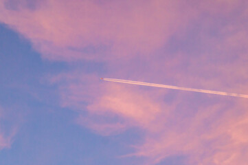 Trace in an airplane in the sky against the sunset pink sky