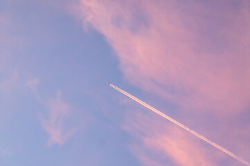 Trace in an airplane in the sky against the sunset pink sky