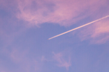 Trace in an airplane in the sky against the sunset pink sky