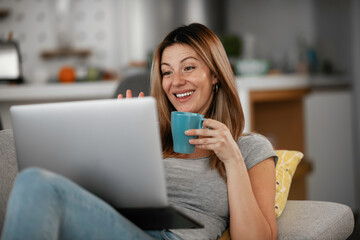 Beautiful woman having a video call on a laptop. Young woman enjoying at home.	
