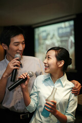 Business people singing karaoke after work