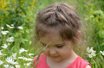 outdoor portrait Cute smiling baby girl in camomile field .Adorable girl with blue eyes and flowers daisies on meadow at summer day.Little child having fun and exploring nature. Copy space