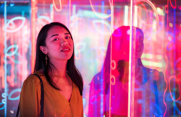 Asian woman portrait lit up by neon lights at night