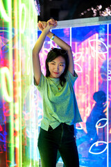 Fototapeta na wymiar Asian woman portrait lit up by neon lights at night