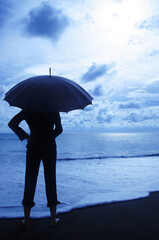 Businesswoman holding an umbrella on the beach