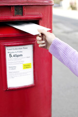Hand putting a letter into the post box
