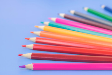 Multi-colored pencils against a blue background. Products for drawing and creativity. Color palette.