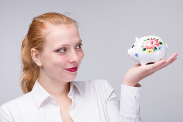 Fototapeta na wymiar young woman looks happily to her piggy bank