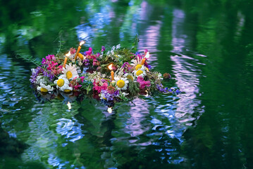 flowers wreath with burning candles swimming in water. old national tradition, fortune telling for...