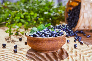 Fresh blueberries in a wooden bowl on a wooden table.