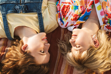 Image of happy two women smiling at each other and lying on blanket