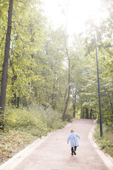 Obraz premium A small child walks in a warm coat in the autumn park and enjoys the sun. The joy of life and the happy moments of growing up.