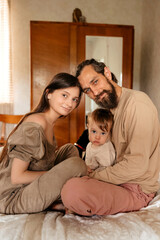 Fototapeta premium Dad, mom and son are playing on the bed.
