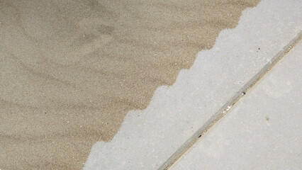 sand of the beach blown on the sidewalk in a wavepattern