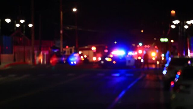 Defocused scene lights flashing fire trucks and police cars people standing in street.