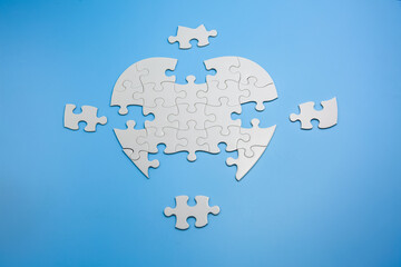 Unfinished white jigsaw puzzle pieces on blue background,  Copy space.