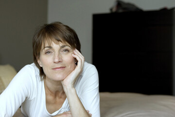 Woman lying forward on the bed smiling at the camera