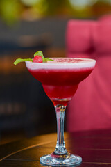 Cold summer alcohol cocktail with ice and fruit in a tall glass on light blurred restaurant or cafe background.