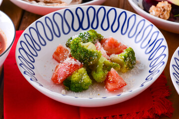 Mixed Salad in a white bowl with brocolli, tomatoes and parmesan cheese. Traditional Italian cuisine, Italian concept.