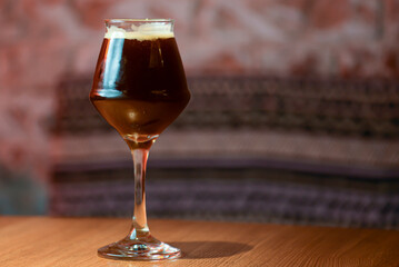 Glass of dark beer on the counter table in bar. Alcohol drink. Food photography concept, copy space.