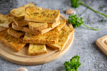 Wooden cutting board with delicious homemade garlic bread on the cement floor