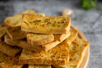 Wooden cutting board with delicious homemade garlic bread on the cement floor